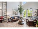 Bright living room with neutral walls, hardwood floors, natural light, and leather sofa with accent pillows at 6039 S Ukraine Cir, Aurora, CO 80015