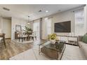 Bright living room features a modern TV console, neutral color palette, and elegant dining area with a decorative chandelier at 3386 Valentia St, Denver, CO 80238