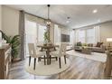 Stylish living and dining area with neutral tones, featuring a modern light fixture and a sliding glass door to the backyard at 3386 Valentia St, Denver, CO 80238