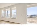 Bright, sunlit living room featuring light wood floors and large windows with neighborhood views and sliding glass door at 918 Congress Pl, Elizabeth, CO 80107