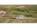 Aerial view of gray home, outbuilding, and large yard with pond, trees and adjacent farm land at 39633 E 160Th Ave, Keenesburg, CO 80643