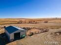 An aerial view of a metal outbuilding with blue roof and horse pen with arid landscape in the background at 39633 E 160Th Ave, Keenesburg, CO 80643