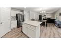 Open-concept kitchen with white cabinets, stainless steel fridge, center island, and adjacent dining area at 21885 Whirlaway Ave, Parker, CO 80138