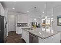 Open kitchen area with a granite island and stainless appliances leads into the living room with dark hardwood floors at 723 176Th Ave, Broomfield, CO 80023