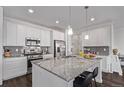 Modern kitchen boasts stainless steel appliances, white cabinets, granite countertops, large kitchen island, and gray backsplash at 723 176Th Ave, Broomfield, CO 80023
