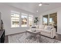 Bright living room featuring three large windows, dark floors, neutral walls, and a sliding glass door to the patio at 723 176Th Ave, Broomfield, CO 80023