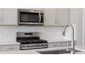 Modern kitchen equipped with stainless steel appliances, gas range, sleek faucet, and white subway tile at 1967 S Coolidge Way, Aurora, CO 80018
