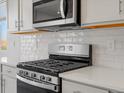 Modern kitchen features a stainless steel gas range, microwave, white subway tile backsplash, and quartz countertops at 1967 S Coolidge Way, Aurora, CO 80018