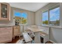 Charming breakfast nook with white benches, light wood table, and bright natural light from two windows at 5477 E Asbury Ave, Denver, CO 80222
