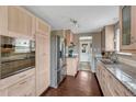Modern kitchen with stainless steel appliances, granite countertops, and light wood cabinets and dark hardwood floors at 5477 E Asbury Ave, Denver, CO 80222