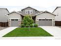 Inviting two-story home with manicured lawn, complemented by symmetrical landscaping and dual garage doors at 14454 Grape Way, Brighton, CO 80602