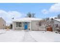 Charming single-story home featuring a covered porch, blue door with wreath, and snow-covered yard at 11 S Perry St, Denver, CO 80219