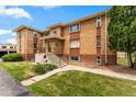 Well-maintained brick apartment building featuring a front lawn, stairs, and ample parking at 1535 Hudson St # 1, Denver, CO 80220
