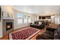 Inviting living room featuring a cozy fireplace, hardwood floors, and ample natural light from large windows at 6173 Eldora St, Golden, CO 80403