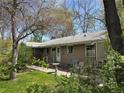 Relax on the backyard patio with a bird bath, surrounded by green grass and mature trees at 1950 Glen Shiel Dr, Lakewood, CO 80215