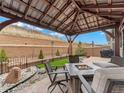 Covered back patio seating area with a fire pit, rock detail, and partial privacy fence at 4538 Hidden Gulch Rd, Castle Rock, CO 80104