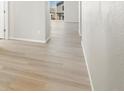 Bright hallway featuring modern light wood-look floors and a view to the deck in the background at 8879 Sedalia St, Commerce City, CO 80022