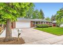 Single-story brick home with attached garage, well-kept lawn, and long concrete driveway at 13558 E Center Ave, Aurora, CO 80012