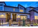 Stylish townhome featuring modern design, a mix of brick and siding, and an inviting fenced front yard at twilight at 12339 W 58Th Ct, Arvada, CO 80004