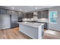 Modern kitchen with gray cabinets, stainless steel appliances, an island, and light hardwood floors at 8585 Eckley St, Littleton, CO 80125