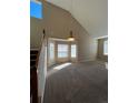 Spacious carpeted living room featuring vaulted ceilings, natural light, and modern lighting fixture at 1148 S Duquesne Cir, Aurora, CO 80018