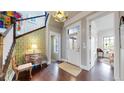 Charming foyer with hardwood floors, designer wallpaper, complemented by a vintage chest and stairway at 9437 E 51St Dr, Denver, CO 80238