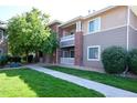 Well-maintained condo exterior featuring brick accents, neutral siding, and mature trees with lush landscaping at 8481 W Union Ave # 2-201, Littleton, CO 80123