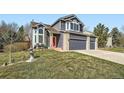 Charming two-story home featuring a red door, three-car garage, and well-maintained lawn at 16442 Bluebonnet Dr, Parker, CO 80134