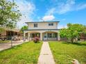 Inviting two-story home with a covered porch, walkway, and beautiful front yard landscaping at 6671 Grove St, Denver, CO 80221