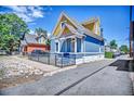 Blue home with yellow trim featuring a secure wrought iron fence and landscaped curb appeal at 523 W 8Th Ave, Denver, CO 80204