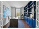 Bright home office with custom blue built-in shelving, a modern desk, and natural light at 15851 Josephine Cir, Brighton, CO 80602