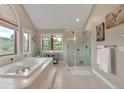 Serene bathroom featuring a soaking tub, glass shower, and bright window views of the lush surroundings at 1091 Colt Cir, Castle Rock, CO 80109