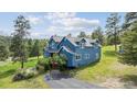 Charming blue two-story home with lush green landscaping and a black asphalt driveway on a sunny day at 5939 S Skyline Dr, Evergreen, CO 80439