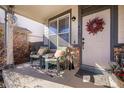 Inviting covered front porch with seating, a wreath, and brick accents at 2321 Ance St, Strasburg, CO 80136