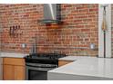 Close up of kitchen with exposed brick backsplash, modern range hood, and modern cabinets at 3354 Vallejo St, Denver, CO 80211