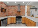 Kitchen with stainless steel appliances, modern cabinets, exposed brick, and light countertops at 3354 Vallejo St, Denver, CO 80211