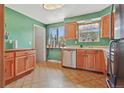 Cozy kitchen with wooden cabinets, laminate countertops, green walls, and views from the window at 6180 W 77Th Pl, Arvada, CO 80003