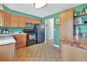View of a kitchen with wood cabinets, black appliances, green walls, and unique checkered flooring at 6180 W 77Th Pl, Arvada, CO 80003