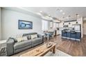 Open-concept living room and kitchen featuring hardwood floors, modern lighting, and stainless steel appliances at 19197 E 64Th Ave, Denver, CO 80249