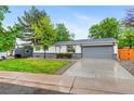 Ranch-style home with lush green lawn, mature trees, and a spacious two-car garage at 4672 S Lewiston Way, Aurora, CO 80015