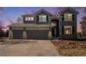 Two-story house with gray siding, stone accents, and a two-car garage at dusk at 11729 Elmer Linn Dr, Longmont, CO 80504