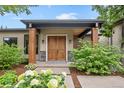 Inviting front entry with a covered porch, attractive double doors, and professionally landscaped garden at 8250 W 63Rd Ave, Arvada, CO 80004