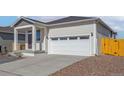 Charming home exterior highlighting a two-car garage, covered porch, and well-maintained landscaping at 9462 Yampa Ct, Commerce City, CO 80022