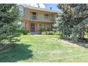 Beautiful townhome featuring a classic brick facade, a welcoming balcony, and a well-manicured lawn at 8780 E Yale Ave, Denver, CO 80231
