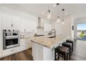 Modern kitchen with granite counters, white cabinets, stainless appliances, and breakfast bar seating at 7169 Canyon Sky Trl, Castle Pines, CO 80108