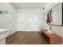 Bright entryway with hardwood floors, modern bench, and white doors leading to other rooms at 2660 Julian St, Denver, CO 80211