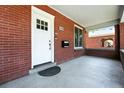 Inviting covered porch featuring a brick facade, white door, and space for outdoor seating at 2660 Julian St, Denver, CO 80211