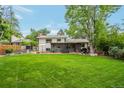 Spacious backyard featuring a large grassy area, mature trees, and a patio at 10991 E Vassar Dr, Aurora, CO 80014