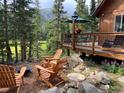Relaxing outdoor space featuring Adirondack chairs and a fire pit, set against a backdrop of trees at 563 Brook Dr, Idaho Springs, CO 80452