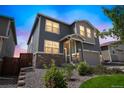 Two-story house with gray and beige siding, a two-car garage, and landscaping, dusk lighting at 4245 S Nepal Cir, Aurora, CO 80013